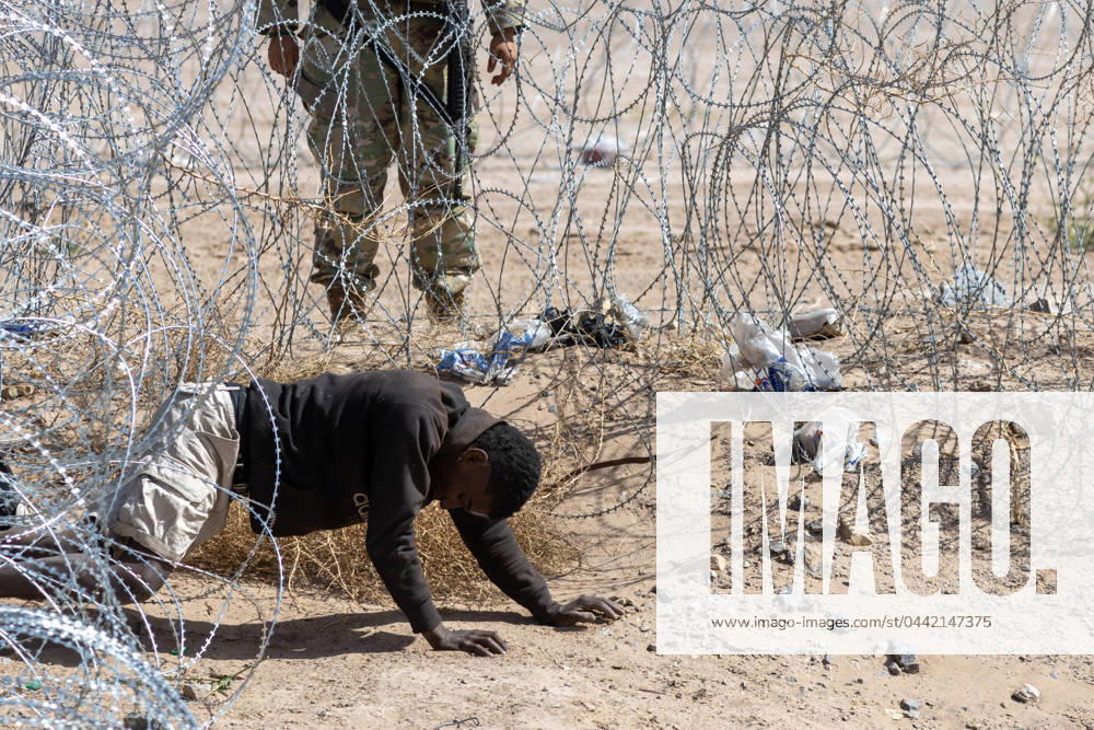 A man crawls under the barbed wire after attempting to cross the border, and a Texas National Guard agent orders him to return to Mexico - ZUMAp241 20240324_zip_p241_010