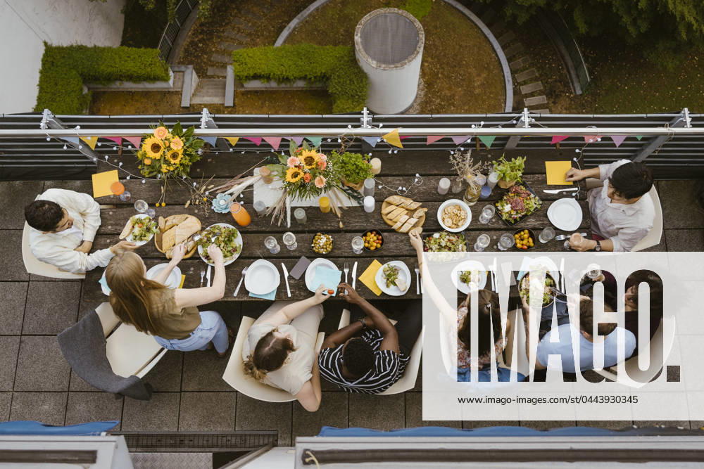Directly above view of male and female friends having food while sitting at dining table during dinner party in balcony Germany, Berlin, model released, property released