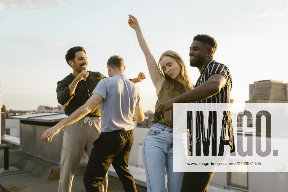 Carefree group of male and female friends dancing together on building terrace Germany, Berlin, model released