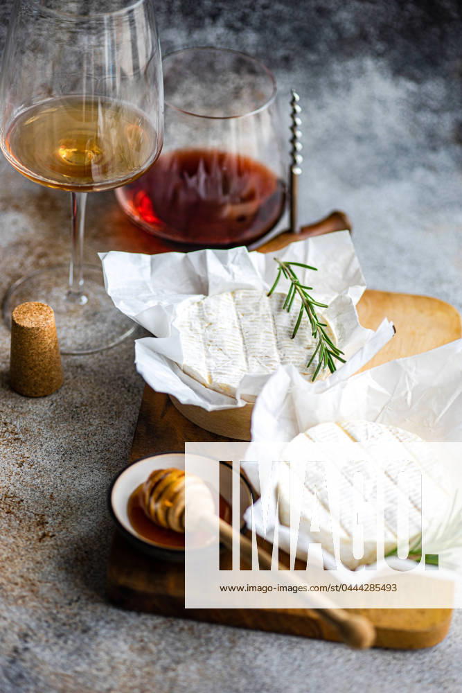An exquisite display of Brie cheese complemented by honey, rosemary, and a pairing of red and white wine. Model Released AnnaBogush_ID20594_608288_007