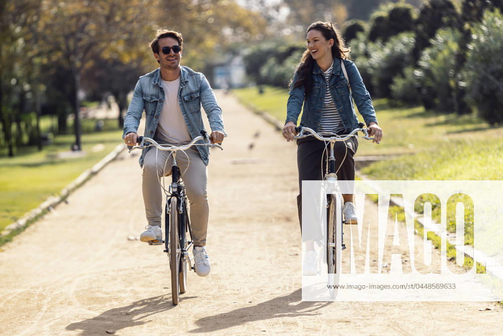 Happy couple cycling and having fun on footpath at park model released, Symbolfoto, JSRF02985