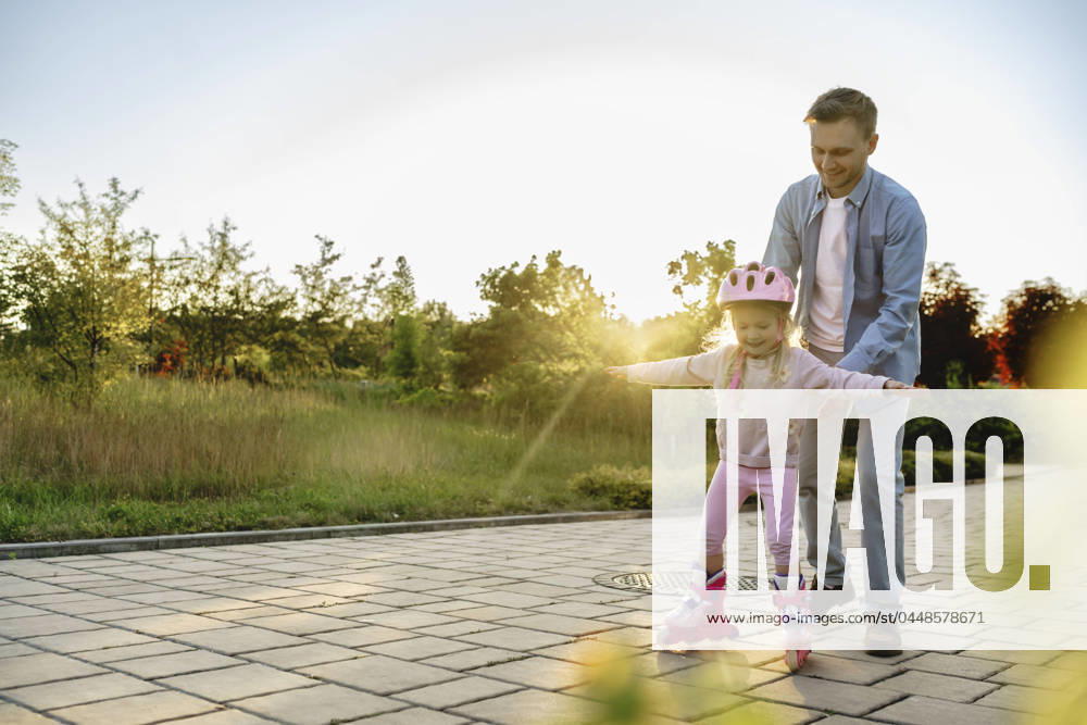 Daughter learning to roller skate with father on footpath model released, Symbolfoto, NSTF00044