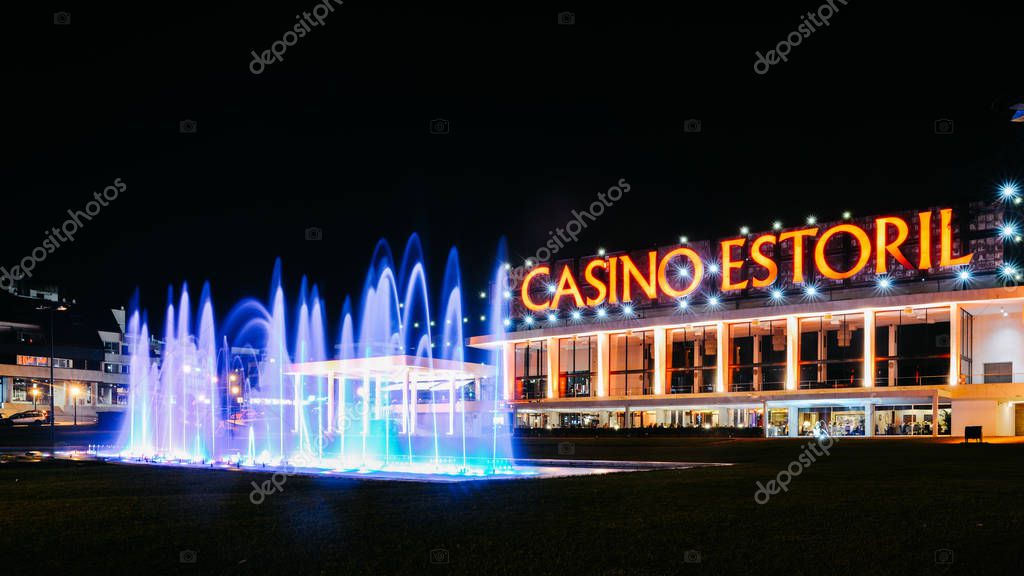 Estoril, Portugal - Sept 8th, 2018: Facade of the Casino Estoril with colourful fountain show at night, one of the largest casinos in Europe and inspiration for Ian Flemings Casino Royale