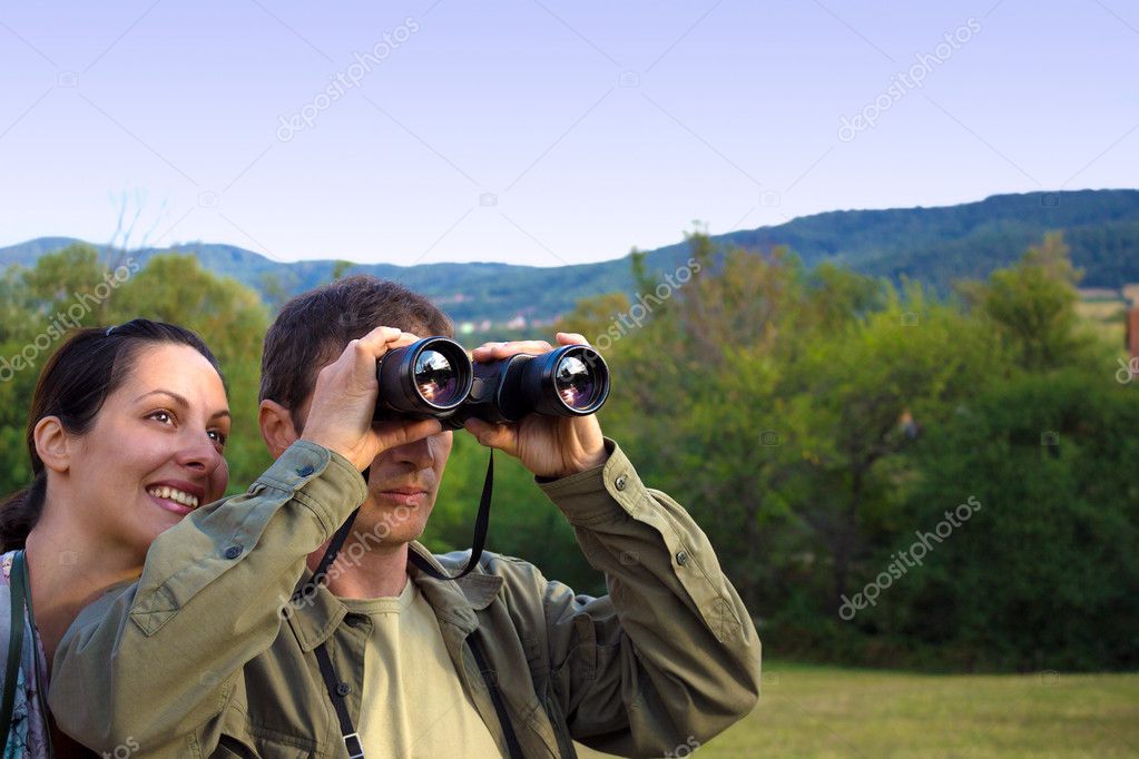 Couple with binoculars watching birds in nature, photography model released