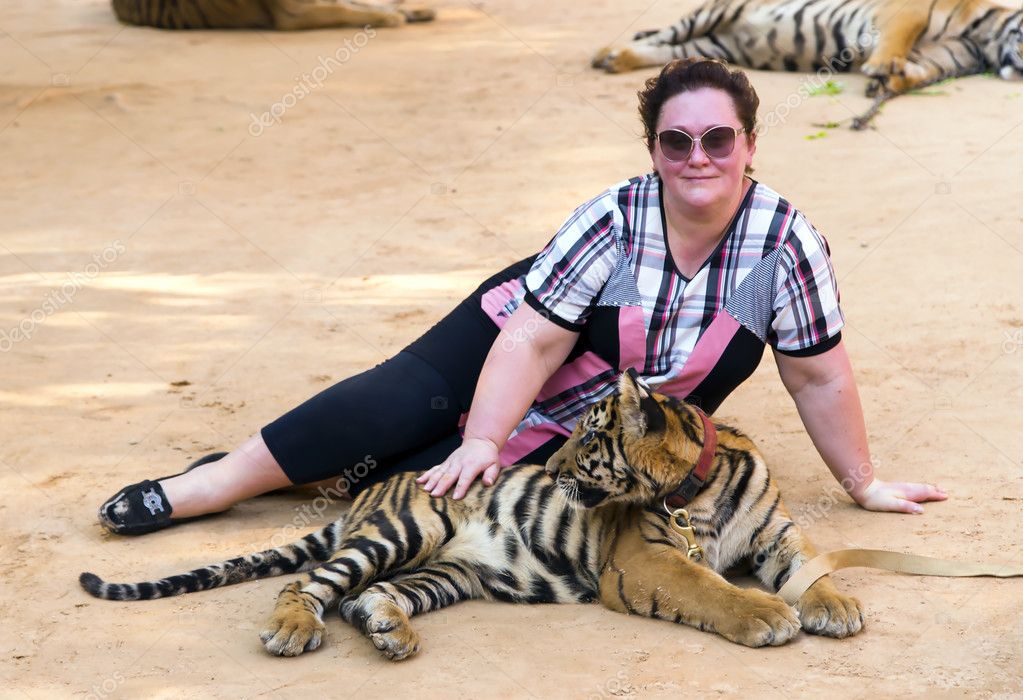 Woman with a little tiger are in Wat Pa Luangta Bua Yannasampanno Forest Monastery, Tiger Temple, Kanchanaburi, Thailand. model released