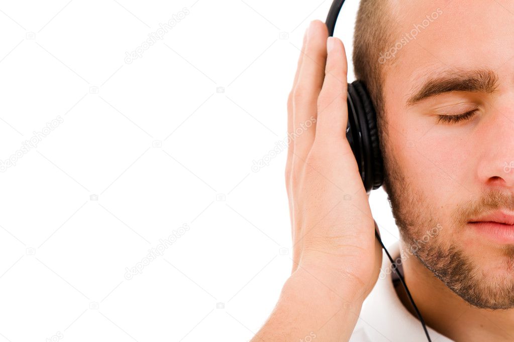 A young man with eyes closed listening to music with headphones, isolated on white model released