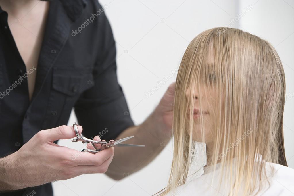 Man cutting a young womans hair in the hairdressers model released