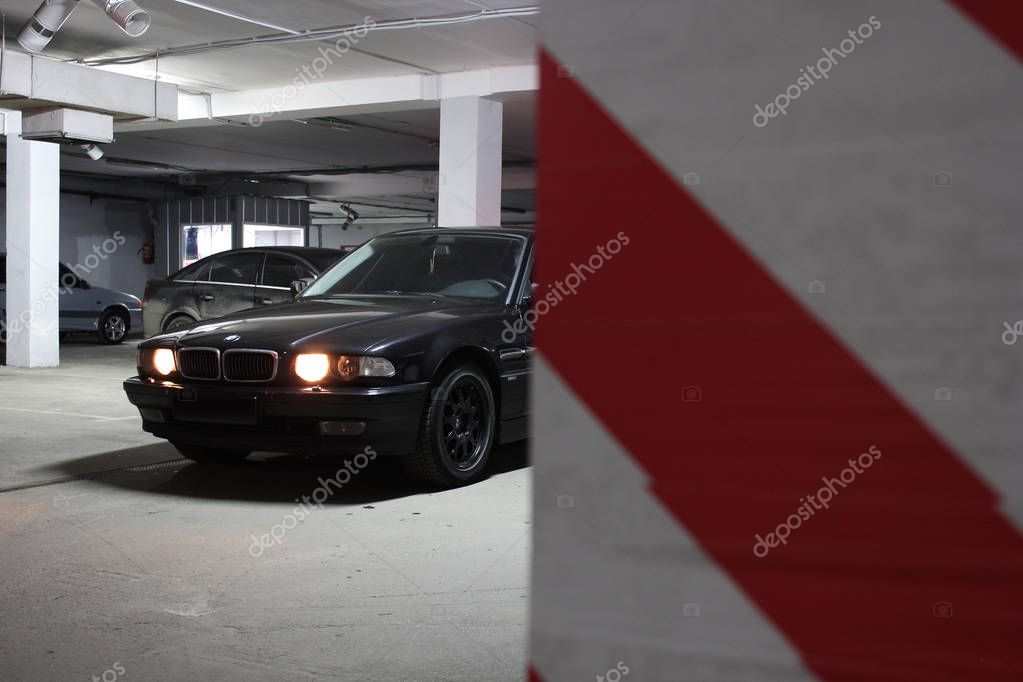 Underground parking. BMW 7 (e38) in the shadows with glowing lights in low light. Car. Editorial photo.
