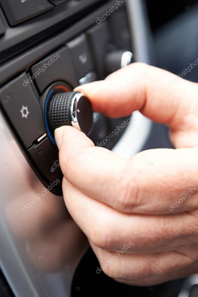 Close Up Of Hand Adjusting Car Air Conditioning Control On Dashboard