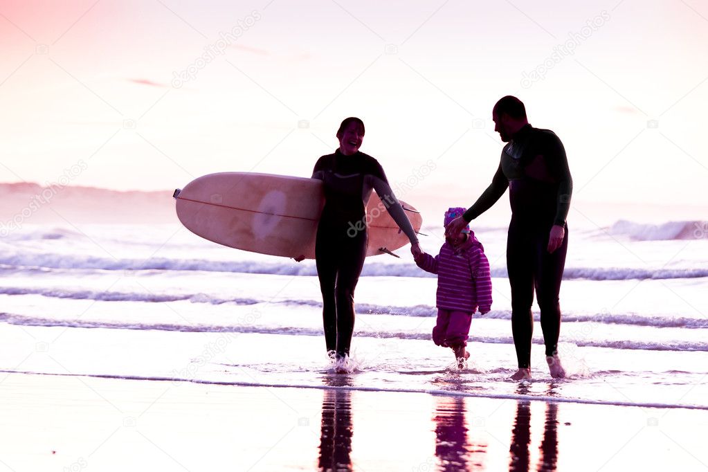 Female surfer and her familly walking in the beach at the sunset model released
