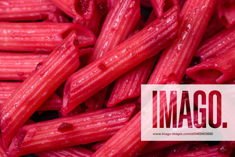 Delicious penne pasta with beets, cheese, salt and spices Delicious penne pasta with beets, cheese, salt and spices on a dark concrete background