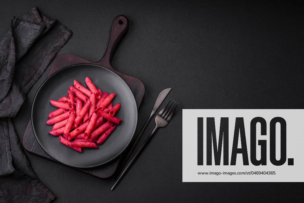 Delicious penne pasta with beets, cheese, salt and spices Delicious penne pasta with beets, cheese, salt and spices on a dark concrete background