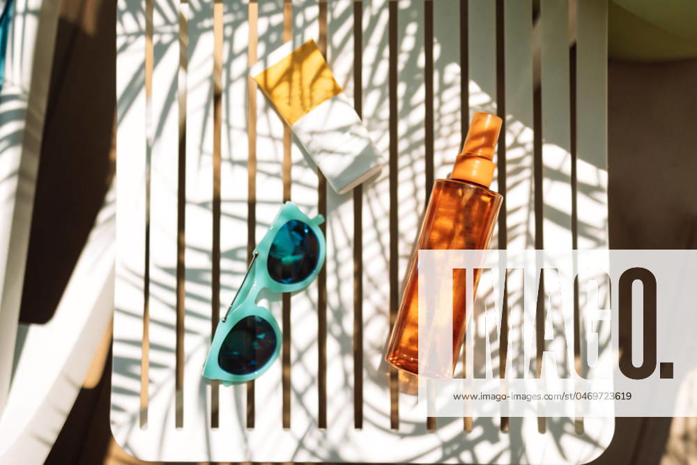 Sunscreens, sunglasses and a delicious chilled cocktail on the pool table Sunscreens, sunglasses and a delicious chilled cocktail on the pool table. Mock-ups of cosmetics and lemonade next to the chaise longue. A delicious cooling drink on vacation at the hotel.