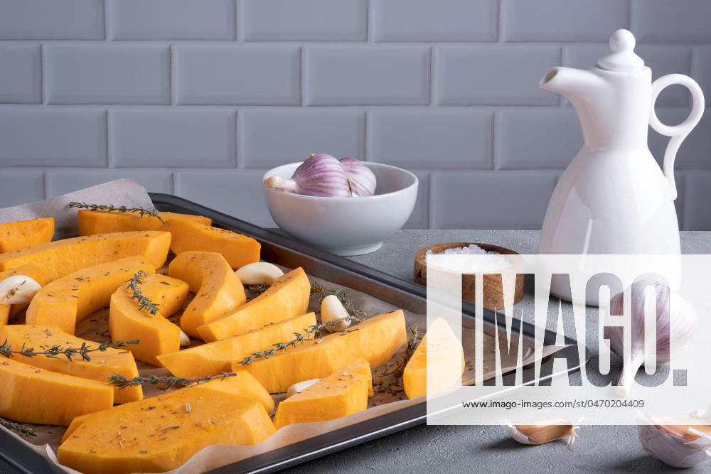 IMAGO Creative, Herbst, Food, Ofenkürbis Pieces of ripe pumpkin prepared for baking Pieces of ripe pumpkin prepared for baking on a baking sheet with olive oil, garlic and dry thyme on the kitchen table. Healthy food. Selective focus.