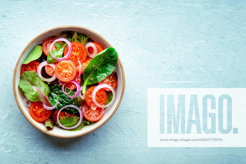 Salad with tomato, fresh leaves, and onions, overhead flat lay shot Salad with tomato, fresh leaves, and onions, overhead flat lay shot. Healthy diet, simple vegan recipe, with copy space