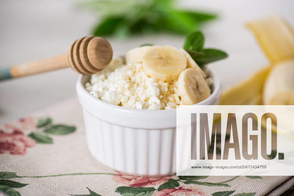 Crumbly organic cottage cheese with honey and bananas in a ceramic bowl crumbly organic cottage cheese with honey and bananas in a ceramic bowl on the table