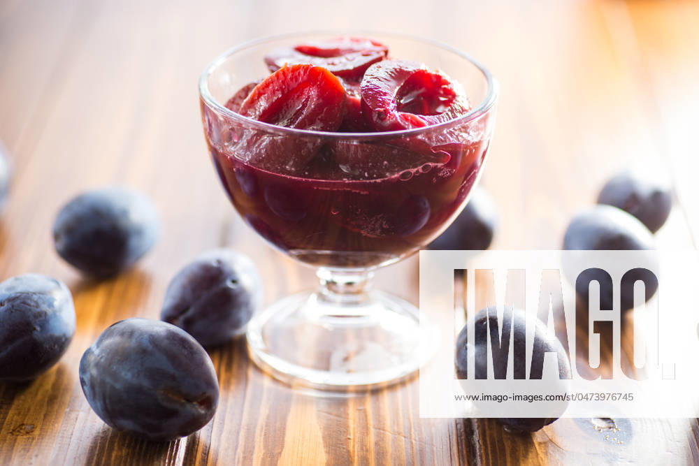 IMAGO Creative, Jahreszeit Sommer, Food, Marmelade kochen Sweet plums in syrup, in a glass bowl . Sweet plums in syrup, in a glass bowl on a wooden table.