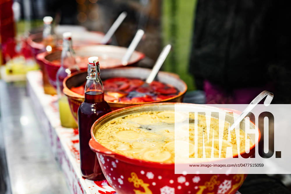 Hot mulled wine on a street food market Beverages fruits and berries hot mulled wine in red pots in street food market. Colorful hot drinks at fair festival outdoors closeup