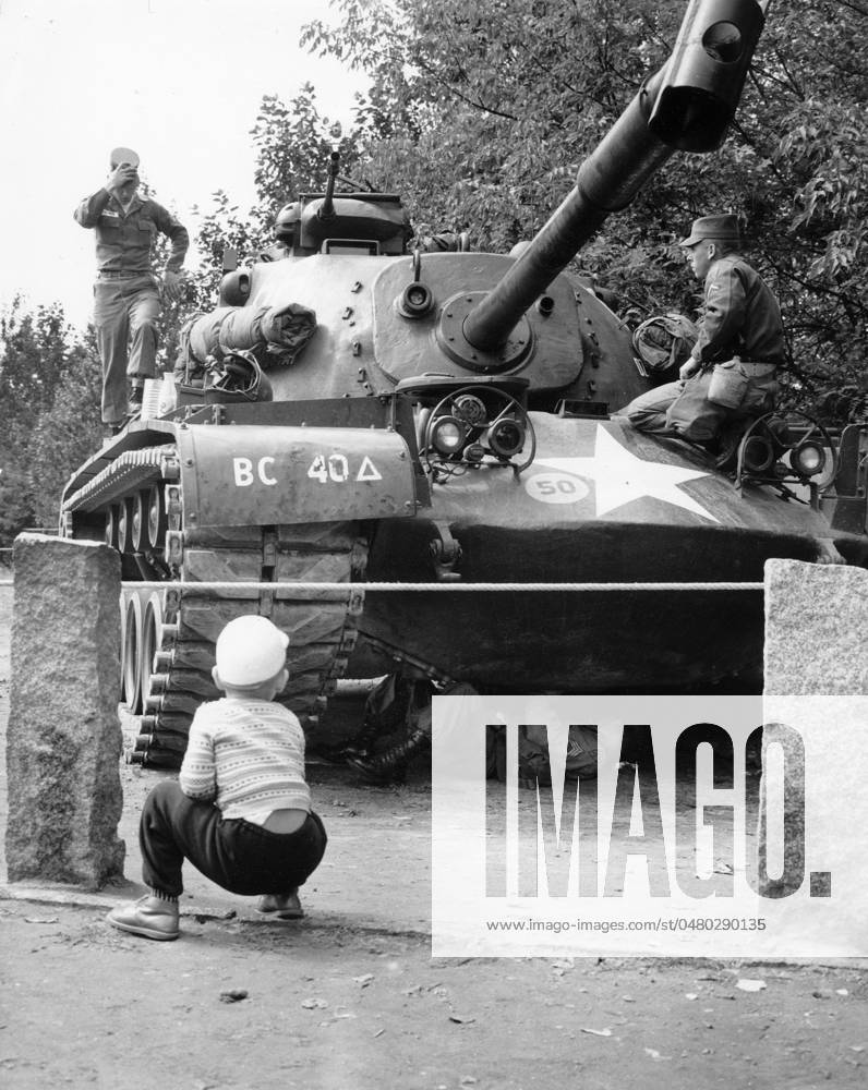 Bau der Berliner Mauer Ein Berliner Junge hockt vor einem US-Panzer, an bzw. unter dem US-Soldaten zu Gange sind, Berlin 1961. Originale Bildbeschreibung: Momentane Situation an den Grenzen Westberlins - Wildernbruchstr. sic. , Berlin
