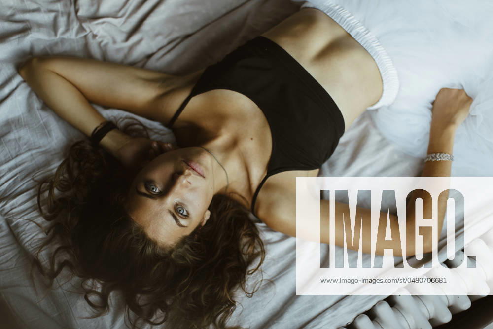 Beautiful woman in sports bra lying on bed at home model released, Symbolfoto property released, MCHF00079