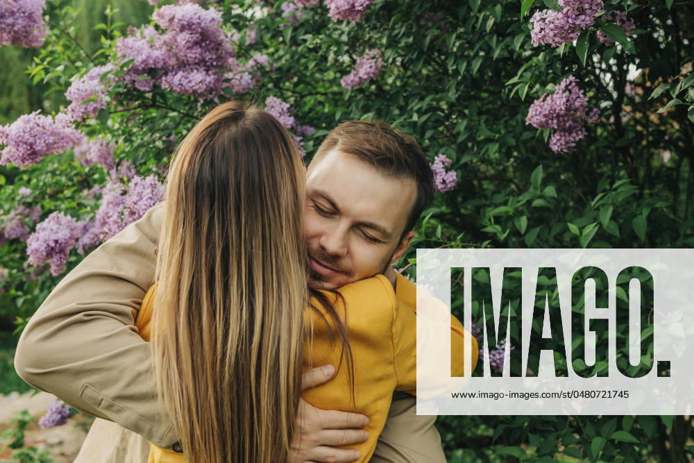 Happy couple hugging each other near lilac tree in park model released, Symbolfoto, VSNF01945
