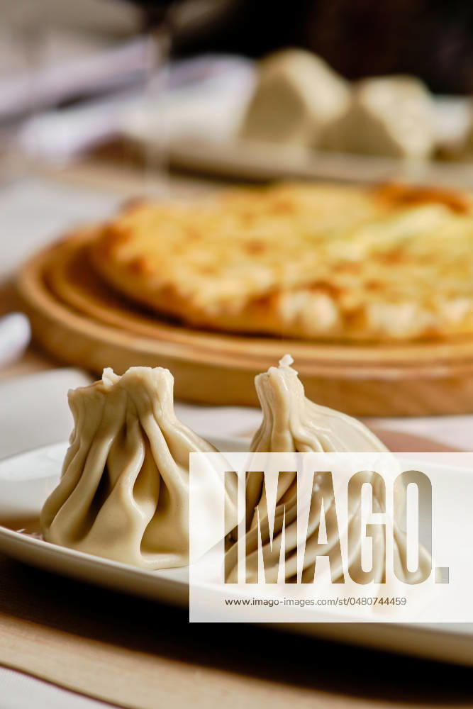 IMAGO Creative, Food, Dumplings A delicious selection of Georgian cuisine, featuring khinkali dumplings on a ceramic plate and khachapuri cheese bread on a wooden serving board in the background Model Released EduardoGarcia_ID21588_633838_002