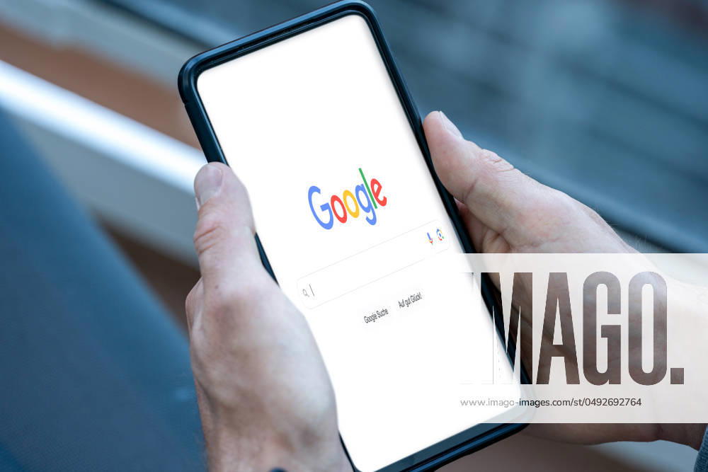 Mobile phone or smartphone in the hand of a person searching for a topic on the Internet in the Google search engine. PHOTOMONTAGE