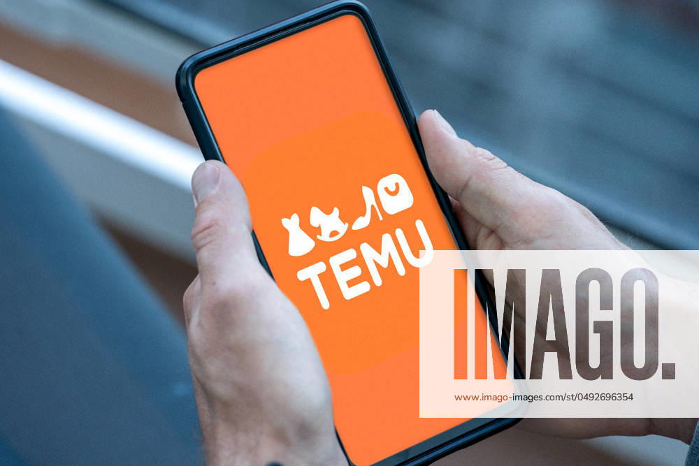 Mobile phone or smartphone in the hand of a person who opens the shopping app or platform Temu of the Chinese digital group PDD on the Internet and the logo appears. PHOTOMONTAGE