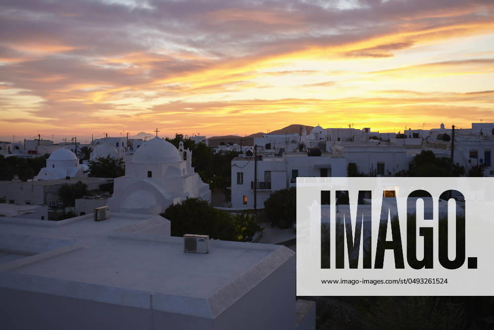 Sunset over a serene town with buildings displaying the iconic whitewashed architecture under a dramatic sky. Folegandros Greece bola01013