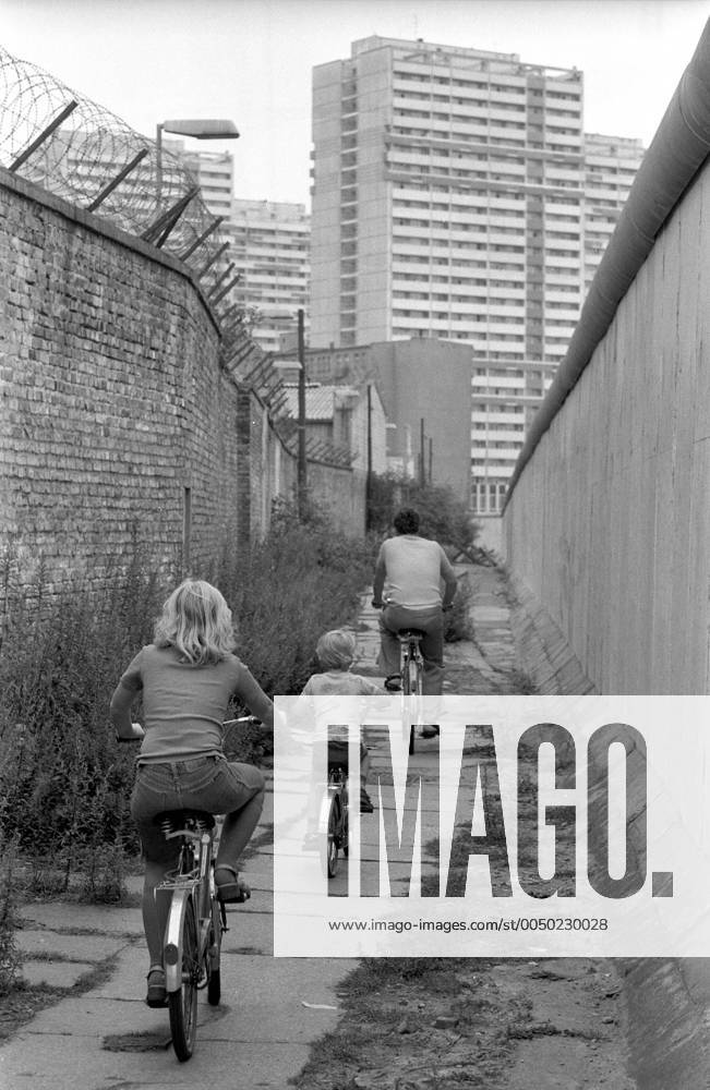 Familie fährt Fahrrad entlang der Berliner Mauer