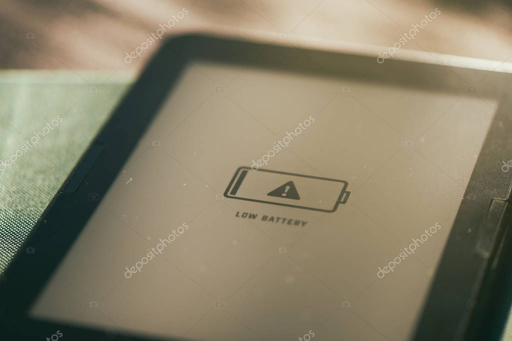 Low battery icon on e-book e-reader screen with warm sunlight