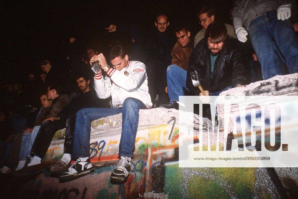 Fall der Berliner Mauer - Junge Männer hämmern auf die Mauer ein