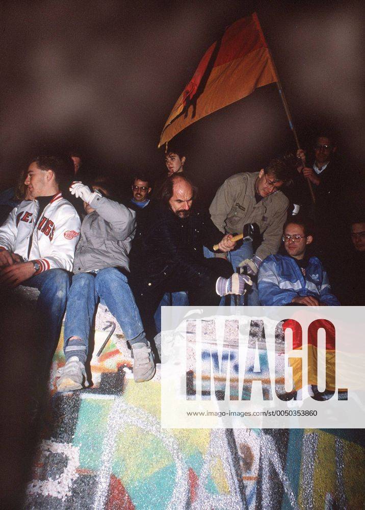 Fall der Berliner Mauer - Junge Männer hämmern auf die Mauer ein
