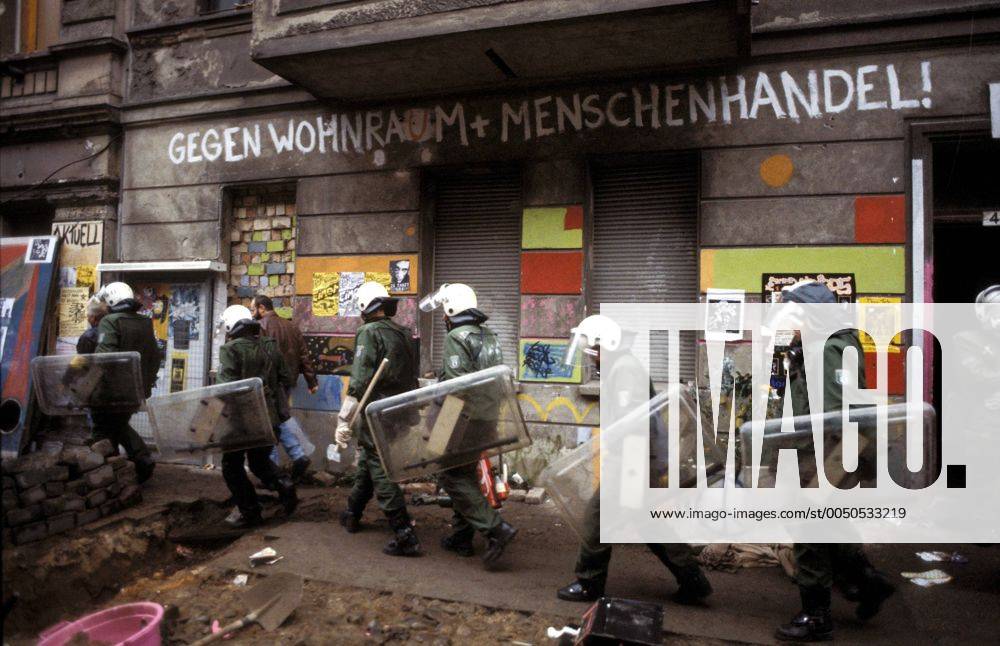 Polizisten laufen vor einer Hauswand mit dem Schriftzug - Gegen Wohnraum und Menschenhandel - während der Räumung besetzter Hauser in der Mainzer Straße in Berlin-Friedrichshain