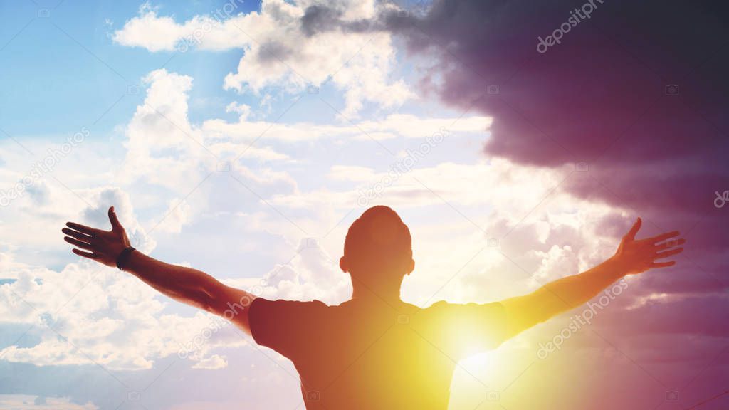 Young man standing with arms outstretched at sunset. Silhouette of the winner model released