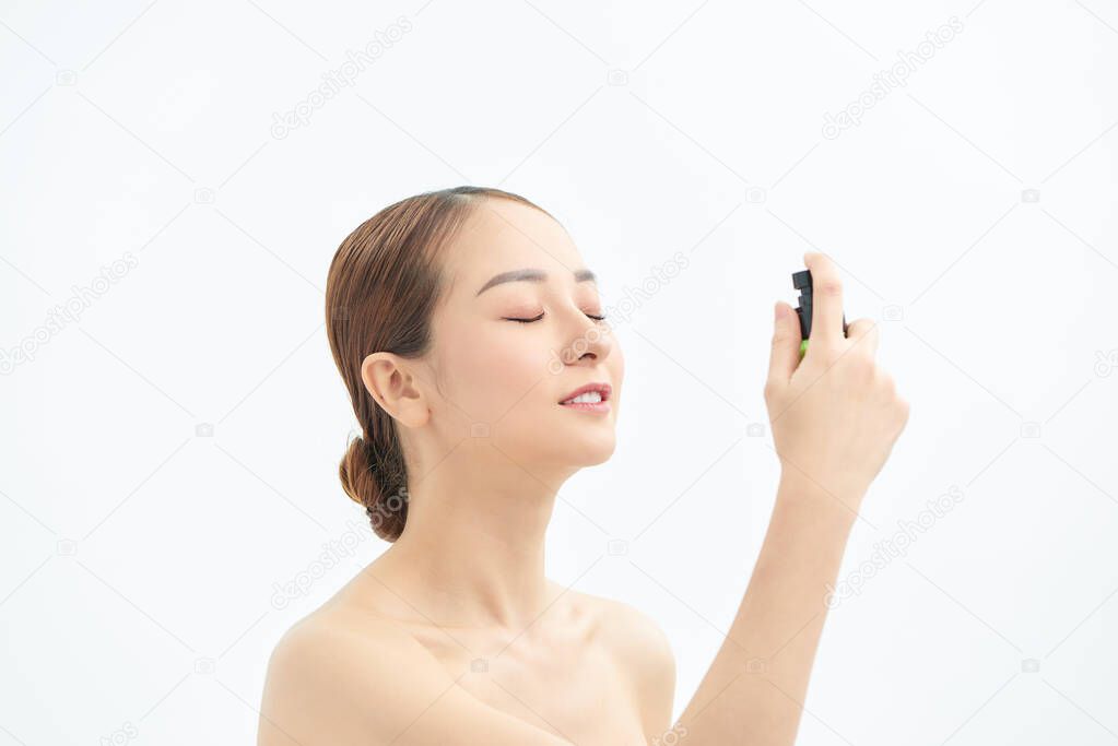 Beautiful Asian woman applying spray water on face on neutral background. model released