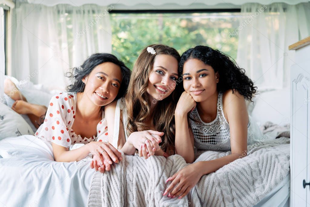 Multi ethnic group of women relax together during summer travel inside the camper van. Vacation, females friendship and beauty concept model released