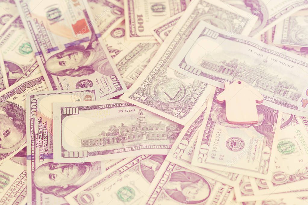 The concept of financial savings to buy a house. Mini model house lying on the dollars banknotes. . Toned.
