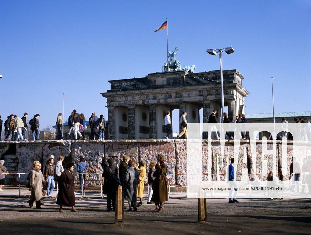 Mauerspaziergang - Menschen stehen auf der Berliner Mauer kurz nach der Wende