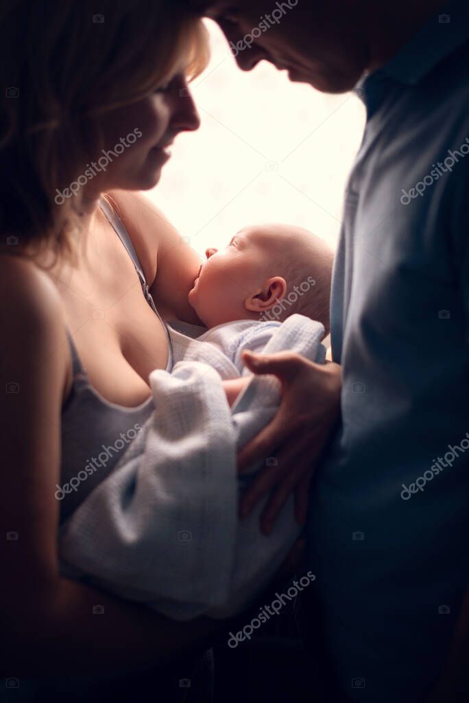 Smiling mother and father holding their newborn baby son at home model released