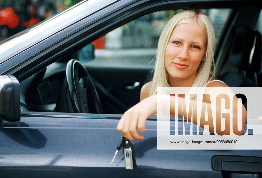 Junge Frau sitzt im Auto, haelt Schluessel in der Hand young woman sitting in automible, holding keys in her hand BLWS014178