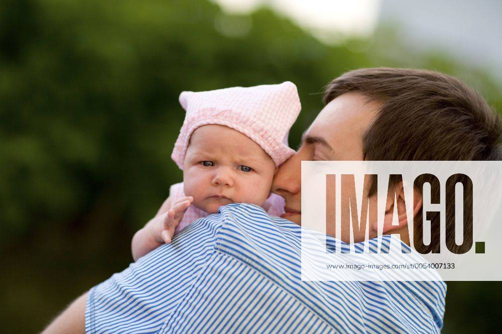 Gluecklicher junger Vater mit seiner Tochter auf dem Arm Happy young father and his baby daughter outdoors at sunny day BLWS233196
