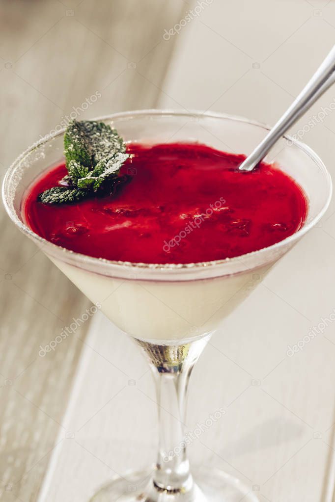 Photo of italian panna cotta dessert with strawberry sirup and mint leaf, soft focus.