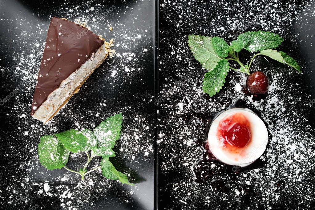 Photo of italian panna cotta dessert with strawberry sirup and cake with nuts and chocolate on the black plate on dark wooden background