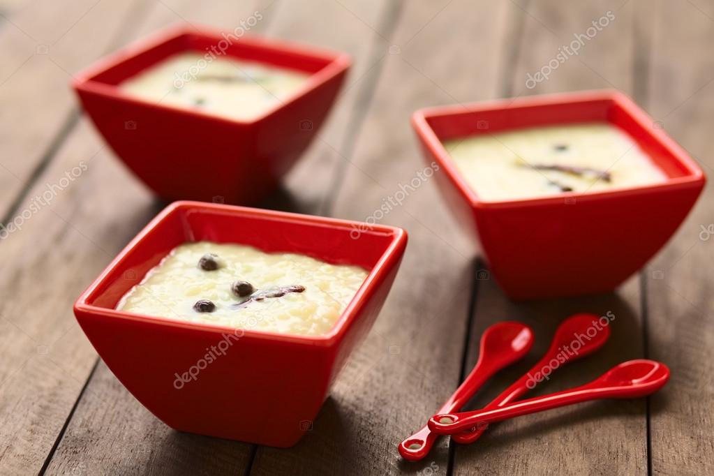 Three red bowls of the Ecuadorian dessert called morocho (coarsely ground white corn) cooked with milk, sugar and spices (cinnamon and allspice), similarly to rice pudding (Selective Focus, Focus on the middle of the lower morocho)