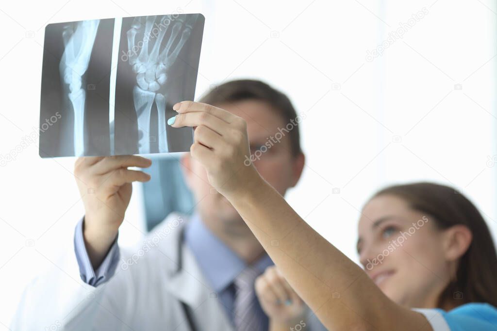 Close-up of female and male hands holding x-ray. Traumatologist and surgeon making diagnosis to patient. Practitioners discussing trauma. Traumatology and healthcare concept model released