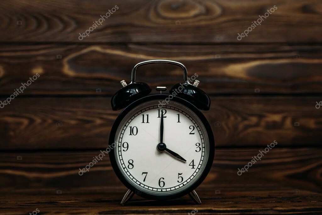 Clock on a wooden background. The clock shows the time of four o'clock in the afternoon. The clock shows the time four o'clock in the morning. An image of a retro clock showing 04:00 pm/am. Copy space