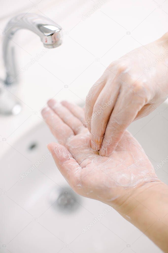 Woman washes her hands by surgical hand washing method. She washes his hands for at least 20 seconds. She washes the palm of his hand. She washes her hands to protect her from Covid-19.