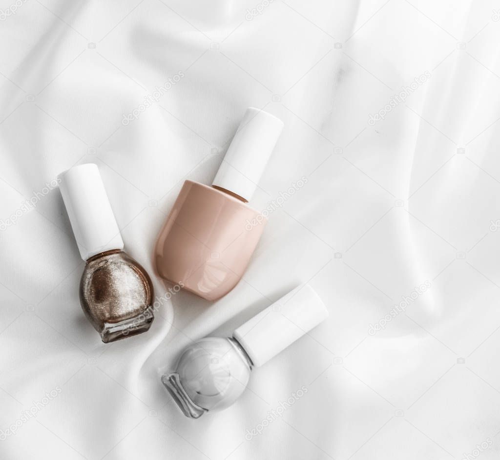 Cosmetic branding, salon and glamour concept - Nail polish bottles on silk background, french manicure products and nailpolish make-up cosmetics for luxury beauty brand and holiday flatlay art design