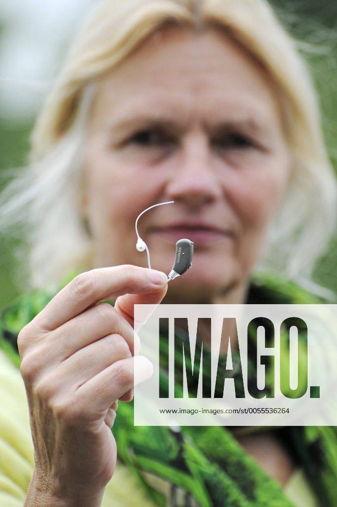 Modernes, kleines Hörgerät in der Hand einer Frau, 55 - 60 Jahre, Schwerhörigkeit iblbab01957490